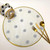 Polka-Dot Round, Black & White Gilt-edged Carole Shiber Designs, decorative tableware with black polka dots on a white background and a gold rim, accompanied by gold cutlery and a black and white polka dot floral embellishment.
