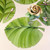 Palm Leaf Placemat Carole Shiber Designs, vibrant green palm leaf placemats arranged on a dining table with a matching napkin folded in a rose shape in a glass vase, and silverware including forks, knives, and spoons. Palm Leaf Placemat Carole Shiber Designs, vibrant green palm leaf placemats arranged on a dining table with a matching napkin folded in a rose shape in a glass vase, and silverware including forks, knives, and spoons.