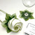 Winter Green-and-White Napkin & Ring Set Carole Shiber Designs, a set of napkins with green leaf accents and a matching ring, displayed on a white surface with a wine glass and a printed card. Winter Green-and-White Napkin & Ring Set Carole Shiber Designs, a set of napkins with green leaf accents and a matching ring, displayed on a white surface with a wine glass and a printed card.