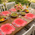 Party Pansy - Pink Carole Shiber Designs, floral-shaped pink placemats on a wooden dining table with plates of salads, wine glasses, and a vase of pink flowers for an outdoor celebration.