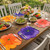 Party Pansy - Pink Carole Shiber Designs, colorful flower-shaped table placemats and a beautifully set outdoor dining table with salad bowls, wine glasses, and a floral centerpiece.