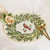 Cardinal in Oval Wreath Placemat by Carole Shiber, decorative table placemat with a green wreath and a central cardinal bird design. Cardinal in Oval Wreath Placemat by Carole Shiber, decorative table placemat with a green wreath and a central cardinal bird design.