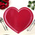 Add a Classic Heart Placemat in Red, a heart-shaped table placemat by Carole Shiber Designs, displayed on a dining table with silverware and a green plant for a romantic table setting.