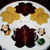 7 Point Leaf - Eggplant/Gold & Bronze Carole Shiber Designs, decorative tablecloth with leaf patterns, set with silverware, cloth napkins, and a small green decorative bowl.