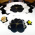 Buttercup Placemat - Black/Gold Carole Shiber Designs, elegant color-blocked black, gold, and cream placemat with a floral design on a white table with matching napkins, utensils, and decorative items.