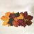Autumn Leaves 3-Pc. Centerpiece, decorative table centerpiece made of colorful autumn leaf-shaped placemats with gold utensils on a white background.