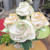 Green Apple Placemat Carole Shiber Designs, decorative white fabric placemats with green and yellow embroidered edges arranged in a bouquet-like display.