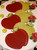 Carole's Red Apple, LIMITED EDITION Carole Shiber Designs table decor featuring large red apple-shaped plates with green leaves and small green apple ornaments, complemented by decorative red roses in glass holders.