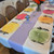 Custom Tablecloths by Carole Shiber Designs, colorful citrus slice-themed table setting with pastel purple and white tablecloths, floral centerpiece, and elegant placemats.