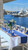 Carole Shiber Designs, custom tablecloths set at a seaside dining table with blue accents, floral centerpiece, and marina view in the background.