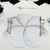 Buttercup Placemat - White/Silver Carole Shiber Designs, elegant floral-shaped placemat with a white and silver design placed on a table setting with silverware and glassware.