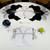 Buttercup Placemat - White and Silver, Carole Shiber Designs, on a dining table with tableware and a green apple.