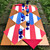 Diagonal Stripes - Blue Carole Shiber Designs, colorful striped paper napkins in red, white, and blue arranged as table mats on a wooden outdoor table with blue glassware and red folded cloth napkins, in a garden setting.