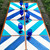 Diagonal Stripes - Blue, a set of four painted tiles with blue and white diagonal stripe patterns, and six blue glass wine glasses arranged on top of them.