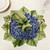 Carole Shiber Hydrangea Pacemat, decorative floral napkin holder with hydrangea motif and green accents, on a table setting with gold cutlery and glassware.