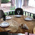 Vintage Leaf Topper - Golden Drape Carole Shiber Designs, elegantly set dining table with glassware and napkins on a wooden table, outdoors on a porch with trees in the background.