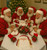 Santa Claus Placemat by Carole Shiber, Christmas-themed placemat featuring Santa Claus design on a table with Santa figurines celebrating Christmas.