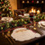 Santa Claus Placemat by Carole Shiber Designs, festive white placemat shaped like Santa’s face on a Christmas dinner table with gold cutlery, evergreen garland, and a glowing fireplace.