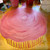 Pink Cupcake Placemat Carole Shiber Designs, round pink placemat with a textured, swirl pattern resembling a cupcake with a striped yellow and pink base.
