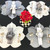 Grey & White, All Set for 4 Carole Shiber Designs - Elegant table setting with striped grey and white placemats, folded napkins with ribbons, gold cutlery, and wine glasses, centered around a vibrant red floral arrangement.