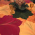 Burgundy & Gold 4 Settings Carole Shiber Designs, decorative table setting with large leaf patterns in burgundy, gold, and green on a wooden table, with gold glasses and a floral centerpiece.