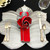 Silver Grey/Black Leaf & Red Carole Shiber Designs, elegant table setting with silver grey and black leaf-shaped placemats, a red and grey napkin folded into a flower, and gold flatware.
