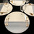 Moonscape Setting Grey & White Carole Shiber Designs, round table placemats with a moonlit design, set with gold flatware, wine glasses, and water glasses.