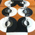 Moonscape Set in Black/White Carole Shiber Designs, a modern table setting with black and white circular placemats, clear wine glasses, and black and white plates on a wooden table. Moonscape Set in Black/White Carole Shiber Designs, a modern table setting with black and white circular placemats, clear wine glasses, and black and white plates on a wooden table.