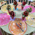 Slice of Summer Life Table Set for 6 Carole Shiber Designs, colorful citrus slice-themed placemats and napkins with vividly colored paper roses in glass vases, set for a festive outdoor gathering.
