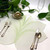 Interlocking Leaf, Pure White/Mint Carole Shiber Designs table decor with leaf-shaped placemat, silverware, green leaves, and a flower decoration.