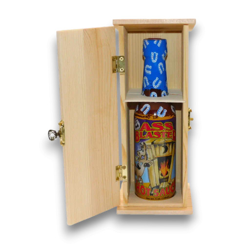 Open wooden outhouse display revealing Ass Blaster Hot Sauce bottle with vibrant, fiery design.