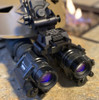 Angled view of a tactical helmet setup featuring two PVS-14 night vision monoculars bridged together using the dual dovetail mount