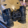 Rear view of a dual tube night vision setup showing two PVS-14s folded in the stowed position on a helmet using the dovetail bridge mount