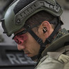 Tactical operator wearing a helmet and the ESS black Crossbow sunglasses with LPL-5 green laser protection lenses during field operations