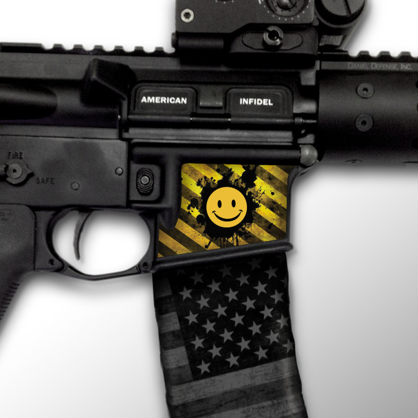Close up side profile of an AR-15 lower receiver featuring the yellow and black hazard stripe Have A Nice Day Mag Well Slaps decal applied to the right side