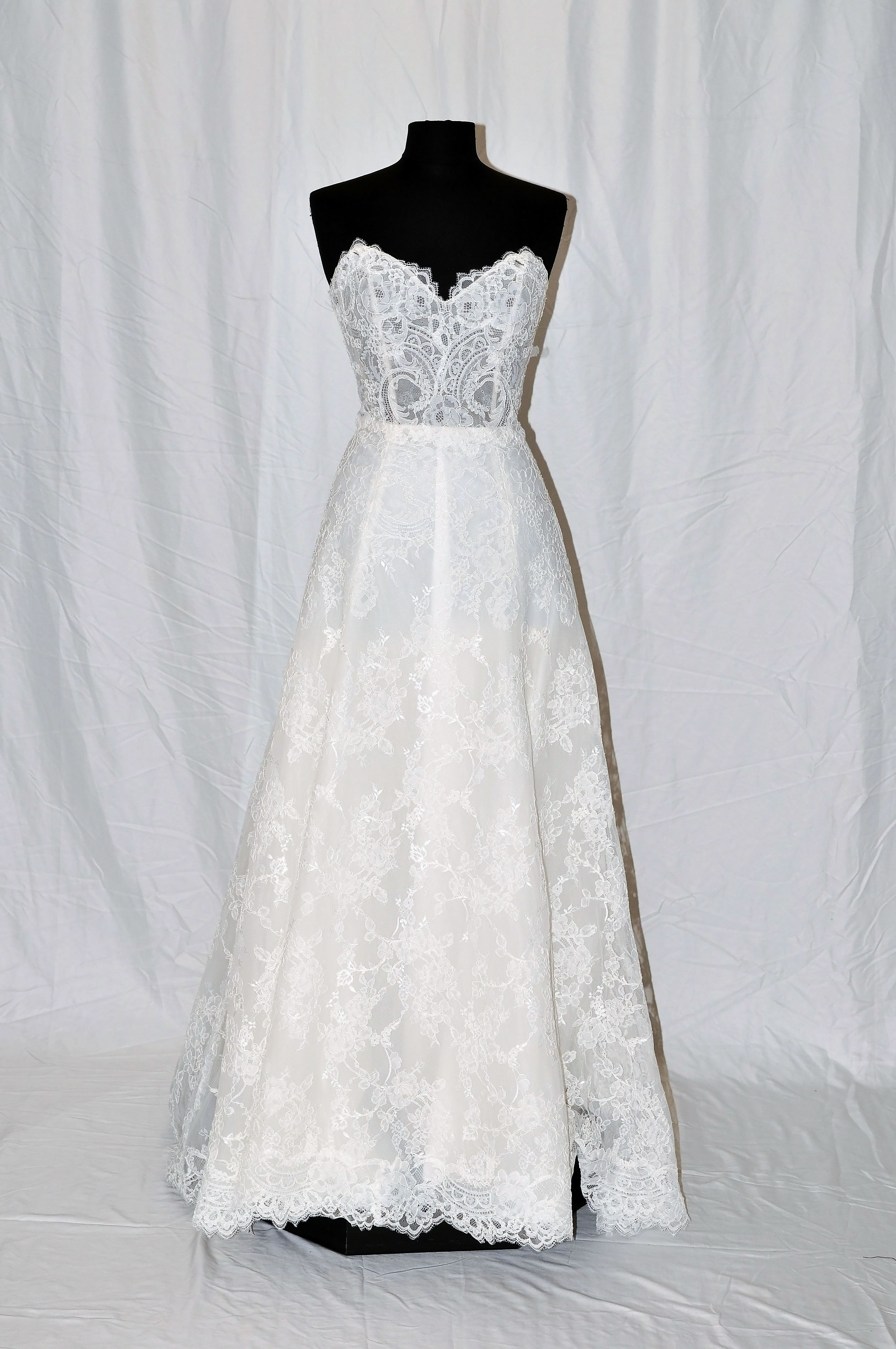 Re-embroidered lace strapless soft a-line gown with scalloped lace neckline and hem.