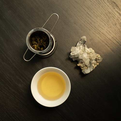 Hand holding a cup of perfectly steeped Sily Milk - milk oolong Siply tea on a black table