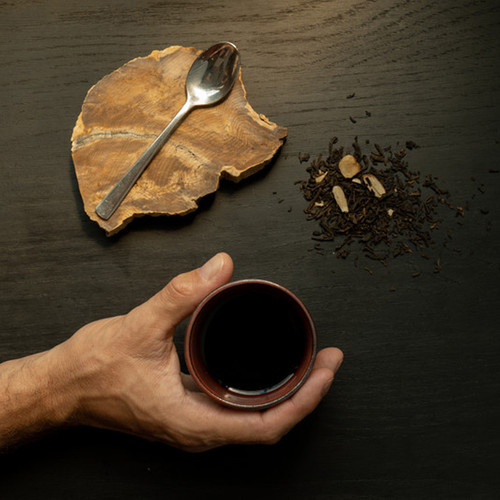 Hand holding a cup of perfectly steeped cup of Scottish Caramel Siply loose leaf tea on a black table Hand holding a cup of perfectly steeped cup of Scottish Caramel Siply loose leaf tea on a black table