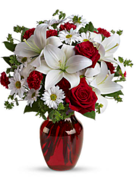 Add some romance to the  season with this rich arrangement of luxurious flowers in classic winter colors. Red roses, snow white lilies and playful daisies are gathered in a ruby red vase she'll use well beyond Valentines.