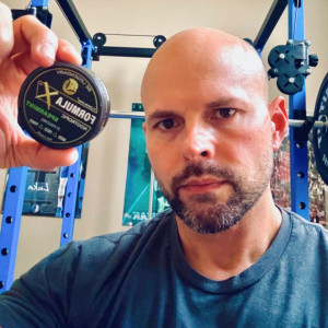 Customer in his home gym holding a Spearmint nootropic pouch can