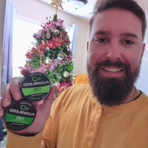 Customer holding Crisp Spearmint and Cool Wintergreen CBD pouch cans in front of the Christmas tree