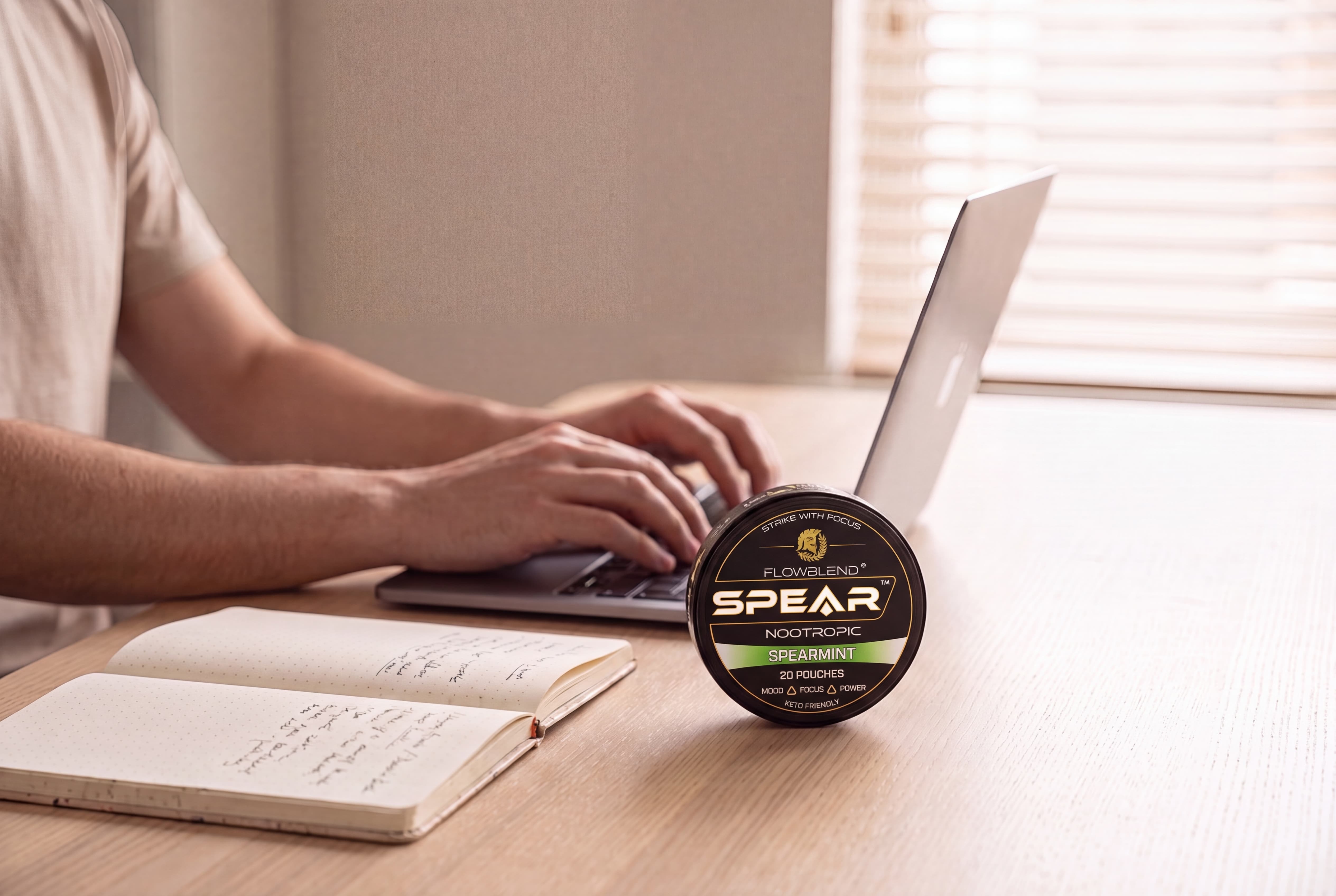 Focused deep work at a desk with a can of SPEAR Cherry Blast nootropic pouches
