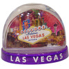 Clear plastic snowdome with a Purple base. Inside has a Vegas welcome sign design with fireworks on the graphics. White snow swirls around on the inside.