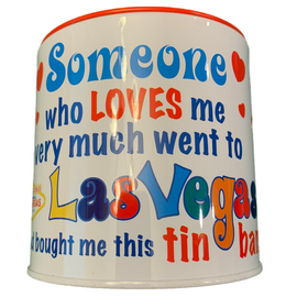 White tin bank in cylinder shape with colorful words Someone who loves me very much went to Las Vegas and brought me this tin bank.