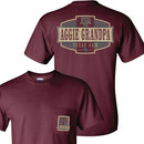 Maroon t-shirt with a tan and gray badge design on the back saying "AGGIE GRANDPA" in maroon ink.