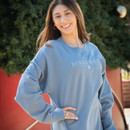 Lifestyle image of a student standing in front of a tree while wearing the Texas A&M Aggies Dainty embroidered crewneck.
