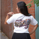 White Texas A&M T-shirt featuring a small Texas A&M College Station graphic on the left chest and a large back graphic with "Howdy" above colorful illustrated "Aggieland" lettering filled with Texas A&M traditions, campus landmarks, and College Station imagery.