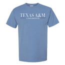 Light blue Texas A&M T-shirt featuring "Texas A&M University" on the front and a large back graphic of Reveille in front of a distressed American flag with the Texas A&M logo.