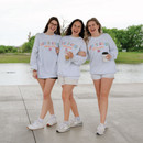 Three girls standing in the park holding coffee while wearing the God is Good crewneck.