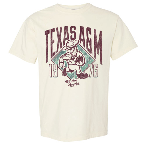 Cream colored Texas A&M graphic t shirt featuring oversized distressed maroon “Texas A&M” lettering, a vintage cowboy mascot illustration holding a football, teal football field background graphics, “1876” numbers on each side, and “Gig ’Em Aggies” script underneath the design